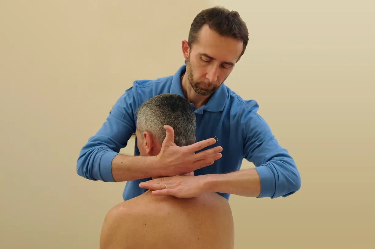 Fisioterapista che tratta la parte superiore della schiena di un paziente senza maglietta.
